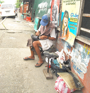 While government executives are squabbling over multi-million transactions this man quietly repairs shoes along a sidewalk on Delgado Street in order to earn a living and feed his family.