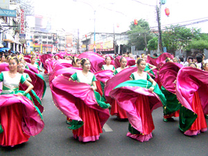 Students garbed in colorful Chinese costumes dance while marching along J.M. Basa St.
