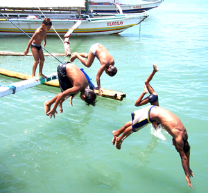 Young boys dive on the water from a pumpboat docking at the Ortiz wharf