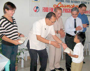 A pre-schooler receives one kilo of rice from Gov. Niel D. Tupas, Sr.