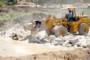 A bulldozer dumps bags of rice damaged by flood