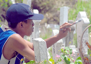 A boy paints the grave of one of the dead inside the Molo Cemetery for P150.00 days ahead of All Saints Day.