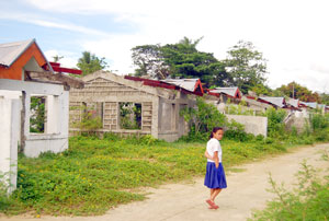 A girl walks past the unfinished housing units for the supposed socialized housing project of the Iloilo city government in Pavia, Iloilo.