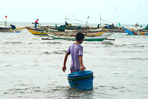 A boy brings tub-like plastic containers to the awaiting fishing boats in the shores of Banate, Iloilo as they prepare to go out to sea.