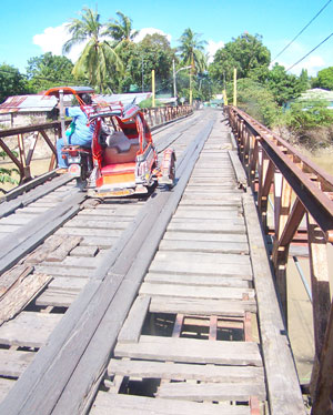 A tricycle traverses this dilapidated bridge in Brgy. Ticud, La Paz district. Pres. Arroyo finally approved the budget amounting to P70 million.