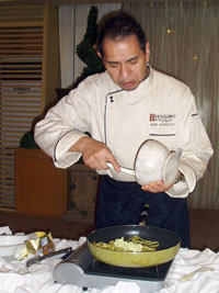 Chef Gene Gonzalez pours ingredients on a pasta dish.