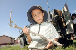 A boy holding a twig, which he makes as his toy gun