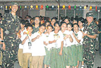 Soldiers pose with elementary and high school students of the University of Iloilo–PHINMA Education Network after lighting a 7-foot tall Christmas tree.