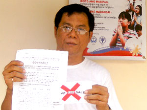 Rev. Fr. Robert Amalay displays the Covenant signed by the voting parishioners in La Paz district and the envelope with red X marked with the words “not for sale”.