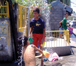 Two boys play with water beside the road in Brgy. San Juan, Molo which celebrated the feast of St. John the Baptist yesterday.