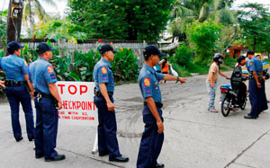 Policemen inspect motorists passing Brgy. Bakhaw in Mandurriao district, Iloilo City